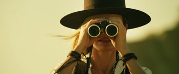 Movie still from “The Counselor” (2013), directed by Ridley Scott – A woman wearing a top hat looking through a pair of binoculars; Close Up shot, Low angle