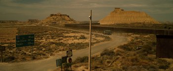 Movie still from “The Counselor” (2013), directed by Ridley Scott – An empty road with a truck driving down the road; Extreme Wide shot, High angle