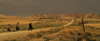 Movie still from “The Counselor” (2013), directed by Ridley Scott – A person walking down a dirt road near a mountain; Extreme Wide shot, High angle