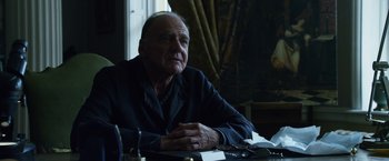 Movie still from “The Counselor” (2013), directed by Ridley Scott – An older man sitting at a table in front of a window; Close Up shot, Low angle