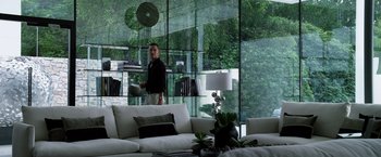 Movie still from “The Counselor” (2013), directed by Ridley Scott – A man standing in front of a window in a living room; Wide shot, Low angle