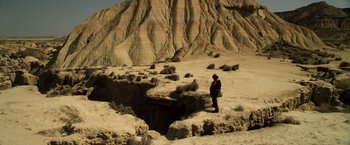 Movie still from “The Counselor” (2013), directed by Ridley Scott – A man standing on a cliff looking into a hole; Extreme Wide shot, High angle