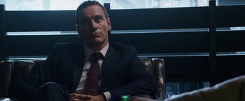 Movie still from “The Counselor” (2013), directed by Ridley Scott – A man in a suit and tie sitting at a table; Close Up shot, Over the shoulder angle