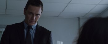 Movie still from “The Counselor” (2013), directed by Ridley Scott – A man wearing a suit and tie in a room; Close Up shot, Over the shoulder angle