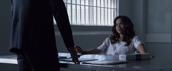 Movie still from “The Counselor” (2013), directed by Ridley Scott – A woman sitting at a table with a man standing next to her; Medium shot, Over the shoulder angle