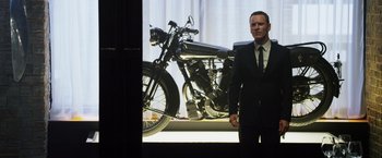 Movie still from “The Counselor” (2013), directed by Ridley Scott – A man standing in front of a black motorcycle; Medium shot, Over the shoulder angle