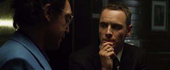 Movie still from “The Counselor” (2013), directed by Ridley Scott – A man in a suit and tie looking at another man in a suit and tie; Close Up shot, Over the shoulder angle