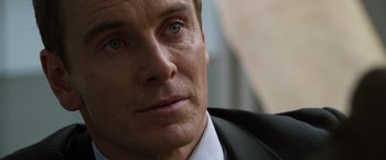 Movie still from “The Counselor” (2013), directed by Ridley Scott – A person wearing a suit and tie; Close Up shot, Over the shoulder angle