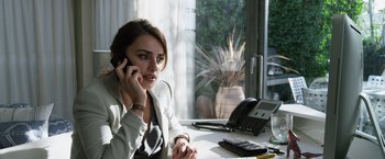 Movie still from “The Counselor” (2013), directed by Ridley Scott – A woman sitting at a desk talking on a phone; Medium shot, High angle