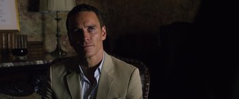 Movie still from “The Counselor” (2013), directed by Ridley Scott – A person sitting in a chair wearing a suit; Close Up shot, Over the shoulder angle