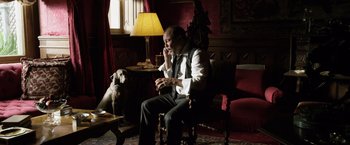 Movie still from “The Counselor” (2013), directed by Ridley Scott – A man sitting in a chair talking on the phone; Medium shot, High angle