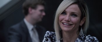 Movie still from “The Counselor” (2013), directed by Ridley Scott – A person smiling with a man in the background; Close Up shot, Over the shoulder angle