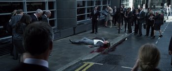 Movie still from “The Counselor” (2013), directed by Ridley Scott – A man in a business suit lying on the sidewalk; Wide shot, High angle