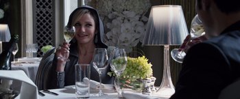 Movie still from “The Counselor” (2013), directed by Ridley Scott – A woman sitting at a table with a wine glass and flower arrangement; Medium shot, Over the shoulder angle