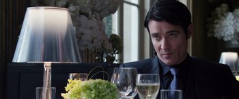 Movie still from “The Counselor” (2013), directed by Ridley Scott – A man sitting at a table with a glass of wine; Close Up shot, Over the shoulder angle