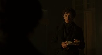Movie still from “The Count of Monte Cristo” (2002), directed by Kevin Reynolds – A man in a dark room holding a book; Medium shot, Over the shoulder angle