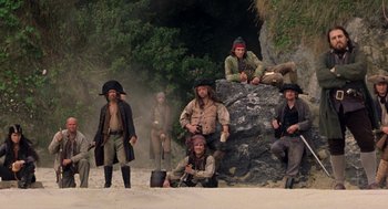 Movie still from “The Count of Monte Cristo” (2002), directed by Kevin Reynolds – A group of people dressed as pirates sitting on a rock; Wide shot, Low angle