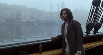 Movie still from “The Count of Monte Cristo” (2002), directed by Kevin Reynolds – A man standing next to a boat on the water; Medium shot, Over the shoulder angle