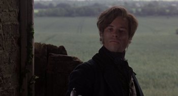 Movie still from “The Count of Monte Cristo” (2002), directed by Kevin Reynolds – A man in a black jacket standing next to a tree stump; Close Up shot, Over the shoulder angle