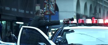 Movie still from “Phone Booth” (2002), directed by Joel Schumacher – A man in a suit is riding in a police car; Medium shot, Low angle