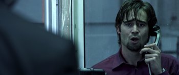 Movie still from “Phone Booth” (2002), directed by Joel Schumacher – A man with long hair and a purple shirt is looking out a window; Close Up shot, Over the shoulder angle