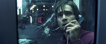 Movie still from “Phone Booth” (2002), directed by Joel Schumacher – A man on the phone with a broken glass window behind him; Close Up shot, Low angle
