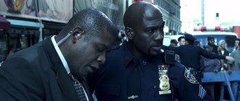 Movie still from “Phone Booth” (2002), directed by Joel Schumacher – Two police officers standing next to each other on a city street; Close Up shot, Over the shoulder angle