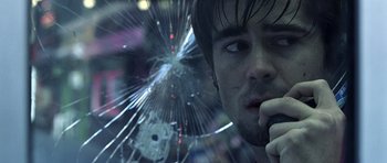 Movie still from “Phone Booth” (2002), directed by Joel Schumacher – A person looking through a broken glass window; Close Up shot, Low angle