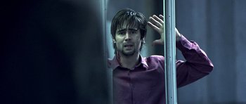 Movie still from “Phone Booth” (2002), directed by Joel Schumacher – A man with long black hair and a purple shirt is looking out of a train window; Close Up shot, Over the shoulder angle