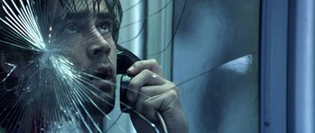Movie still from “Phone Booth” (2002), directed by Joel Schumacher – A man talking on a phone through a window; Close Up shot, Overhead angle