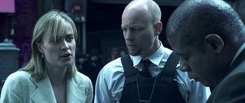 Movie still from “Phone Booth” (2002), directed by Joel Schumacher – A man and a woman standing next to each other in front of another man; Close Up shot, Over the shoulder angle