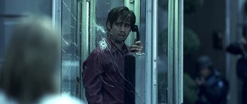 Movie still from “Phone Booth” (2002), directed by Joel Schumacher – A man holding a cell phone while standing in front of a broken window; Close Up shot, Low angle