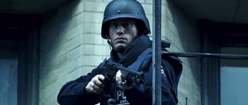 Movie still from “Phone Booth” (2002), directed by Joel Schumacher – A man in a police uniform holding a gun; Medium shot, Low angle