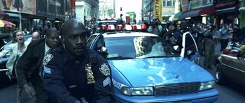 Movie still from “Phone Booth” (2002), directed by Joel Schumacher – A police officer standing in front of a police car; Medium shot, Over the shoulder angle