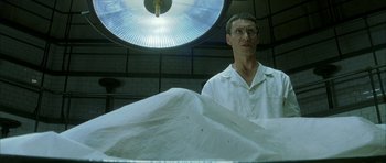 Movie still from “The Crimson Rivers” (2000), directed by Mathieu Kassovitz – A man standing in front of an operating table; Medium shot, Low angle
