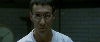 Movie still from “The Crimson Rivers” (2000), directed by Mathieu Kassovitz – A person wearing glasses and a white shirt; Close Up shot, Low angle