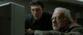 Movie still from “The Crimson Rivers” (2000), directed by Mathieu Kassovitz – Two men looking at a computer screen in a dark room; Close Up shot, Low angle