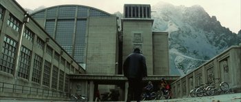 Movie still from “The Crimson Rivers” (2000), directed by Mathieu Kassovitz – A man standing in front of a large building; Extreme Wide shot, Low angle