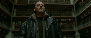 Movie still from “The Crimson Rivers” (2000), directed by Mathieu Kassovitz – A man standing in front of a book shelf in a library; Close Up shot, Low angle