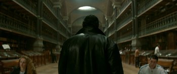 Movie still from “The Crimson Rivers” (2000), directed by Mathieu Kassovitz – A man wearing a black leather jacket in a library; Medium shot, Low angle
