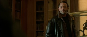 Movie still from “The Crimson Rivers” (2000), directed by Mathieu Kassovitz – A man wearing a leather jacket standing in a room; Close Up shot, Over the shoulder angle