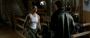 Movie still from “The Crimson Rivers” (2000), directed by Mathieu Kassovitz – A woman in a white tank top is talking to a man in a leather jacket; Medium shot, Over the shoulder angle