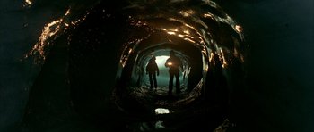 Movie still from “The Crimson Rivers” (2000), directed by Mathieu Kassovitz – Two people are standing in a cave looking at the light; Wide shot, High angle