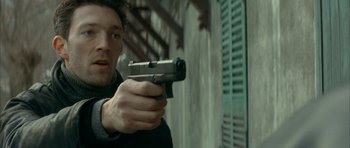 Movie still from “The Crimson Rivers” (2000), directed by Mathieu Kassovitz – A man holding a gun in his hand; Close Up shot, Low angle