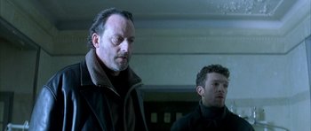 Movie still from “The Crimson Rivers” (2000), directed by Mathieu Kassovitz – Two men standing next to each other in a room; Close Up shot, Low angle