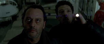 Movie still from “The Crimson Rivers” (2000), directed by Mathieu Kassovitz – Two men are standing in a dark room; Close Up shot, Low angle