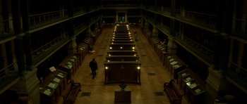 Movie still from “The Crimson Rivers” (2000), directed by Mathieu Kassovitz – A person walking in a room filled with bookshelves; Extreme Wide shot, High angle
