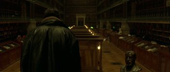 Movie still from “The Crimson Rivers” (2000), directed by Mathieu Kassovitz – A man standing in front of a row of pews in a church; Wide shot, High angle