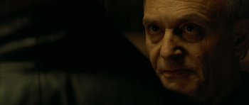 Movie still from “The Crimson Rivers” (2000), directed by Mathieu Kassovitz – An older man with a serious look on his face; Close Up shot, Over the shoulder angle