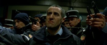 Movie still from “The Crimson Rivers” (2000), directed by Mathieu Kassovitz – A group of men standing next to each other in a room; Close Up shot, Low angle